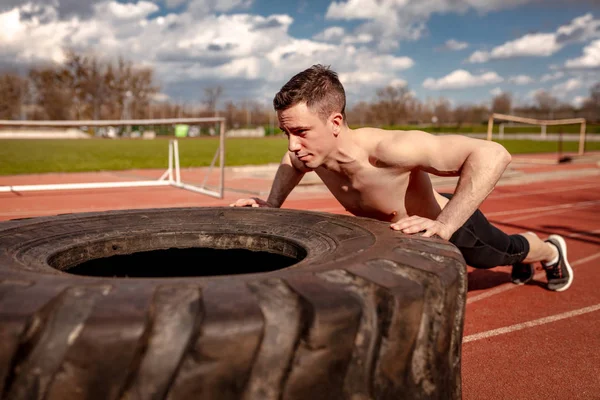 Genç kaslı adam eğitim kasları Stadı için büyük lastik kaldırma