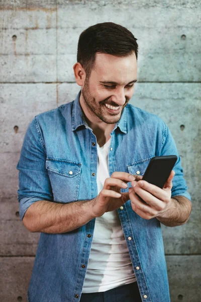 Beton duvar önünde Smartphone kullanarak genç başarılı girişimci