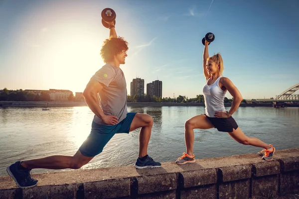 Genç fitness kaç gün batımında nehir tarafından dumbbells ile egzersiz yapıyor