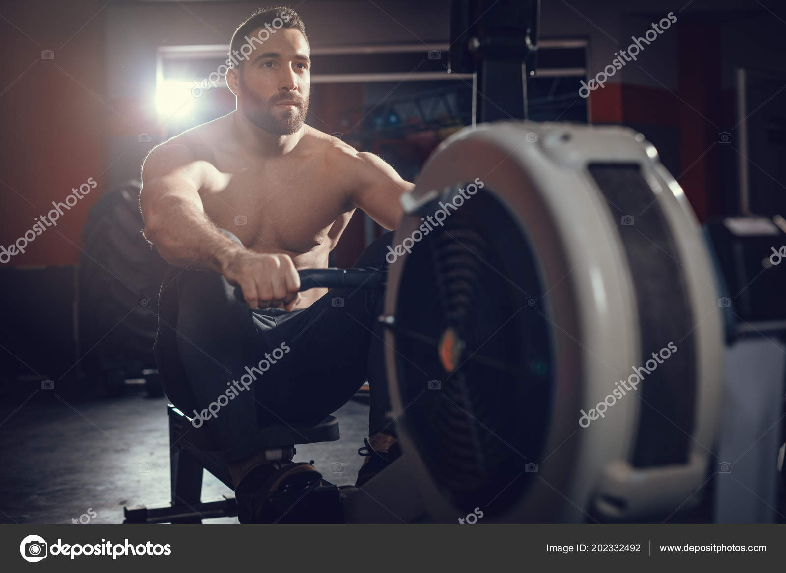 Hombre musculoso en la máquina de remo en el gimnasio