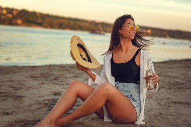 Gün batımında sahilde bira içme sarı sunglesses genç kadın