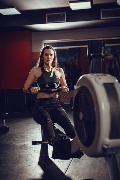 Woman pulling the rowing machine — Stock Photo, Image