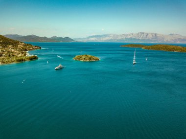 Mavi deniz kıyısında küçük bir kasaba ve yaz saati Yelkenli tekne yüzen ile küçük ada ile havadan görünümü