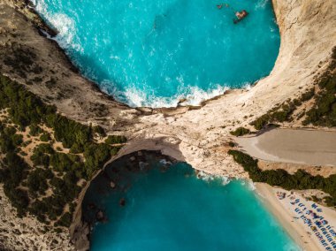 Turkuaz deniz suyu vahşi deniz kıyısı ve sandy ulaşan dalgalar ile havadan görünümü plaj ve dik kayalar güneşli