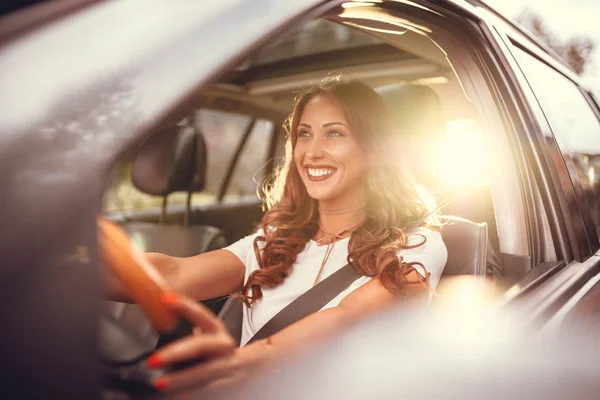 年轻微笑的黑发妇女在日落驾驶新的汽车 — 图库照片