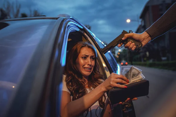 屋外に怖がって若い女性のお金を盗んで銃を持つ危険な犯罪男駐車場 — ストック写真