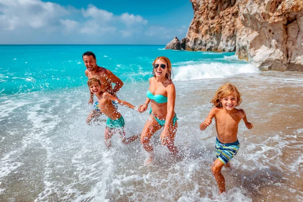 母亲与父亲和孩子在夏天海滩奔跑 — 图库照片