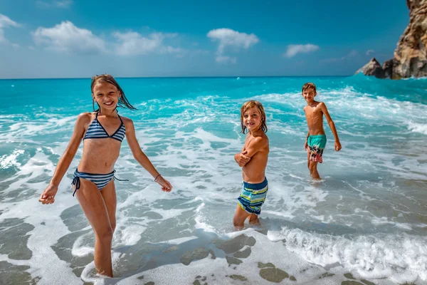 兄弟と姉妹は 暑い夏の休暇中にビーチの海岸で遊ぶ — ストック写真