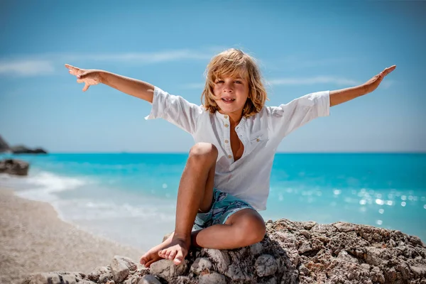 Niedliche Lächelnde Junge Sitzt Auf Meeresfelsen Strand Und Schaut Die — Stockfoto