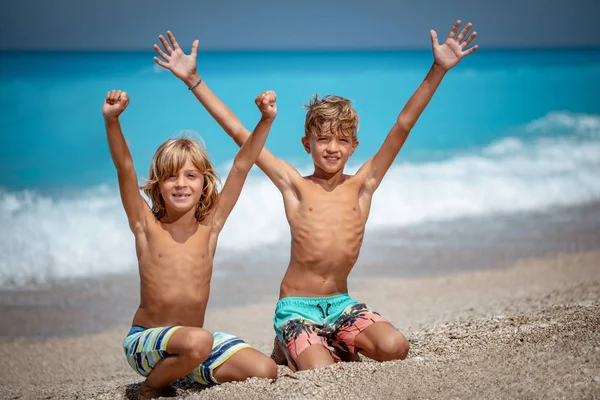 Due Simpatici Fratelli Con Braccia Alzate Seduti Sulla Spiaggia Sorridenti — Foto Stock