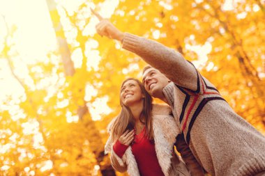 Genç çift güneşli sonbahar ormanda zevk gülümseyen