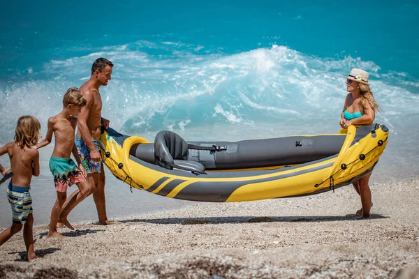 Young family preparing rubber kayak for sailing on beach