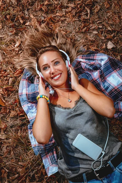 Jeune Femme Souriante Couchée Écoutant Musique Dans Parc Automne — Photo