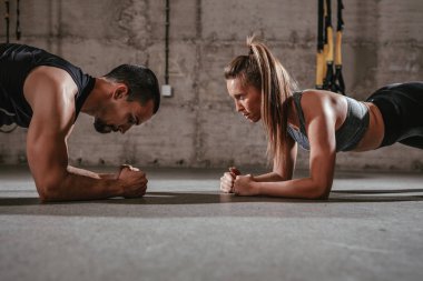 Genç kadının koç ile spor salonunda zor egzersiz yapması
