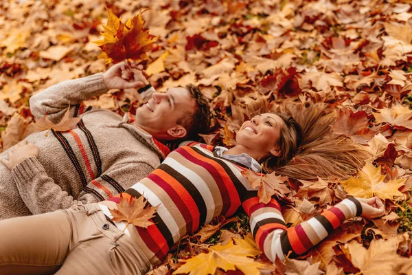 微笑的夫妇躺在地上覆盖着树叶和享受 — 图库照片