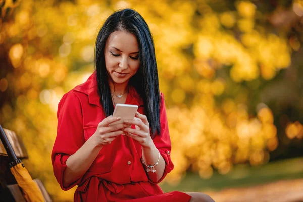 Cheerful Young Woman Red Dress Using Smartphone Autumn Park — Stock Photo, Image