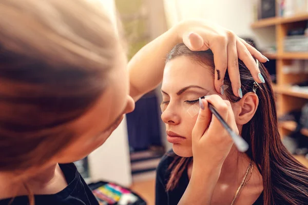 Makeup artist applying eyeliner to model in studio