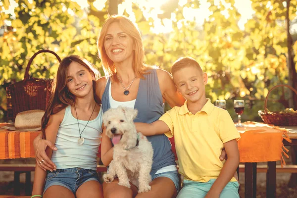 微笑的母亲和孩子与狗在葡萄园野餐 — 图库照片