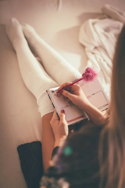 Bonito Jovem Sorrindo Mulher Sentada Cama Fazendo Lista Desejos Natal — Fotografia de Stock