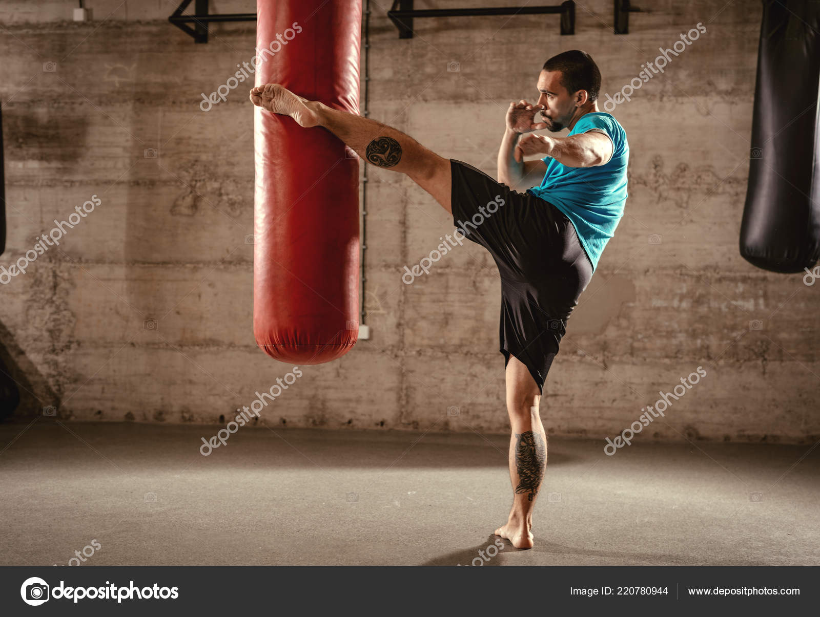 Muscular Man Punching Leg Boxing Bag Cross Fit Training Gym Stock