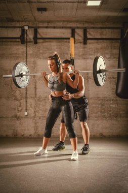 Genç kadının kişisel bir eğitmen ile spor salonunda bodur egzersiz yapması.