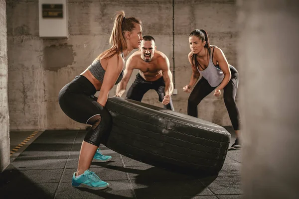 Giovane Donna Muscolosa Lanciando Pneumatico Cross Fit Formazione Palestra Uomo — Foto Stock