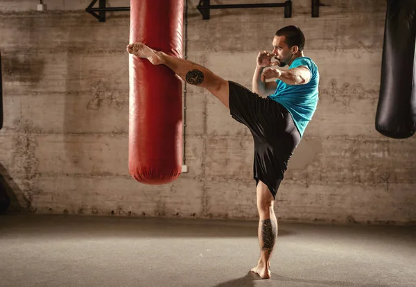 Hombre Musculoso Golpeando Con Pierna Una Bolsa Boxeo Entrenamiento Cross —  Fotos de Stock