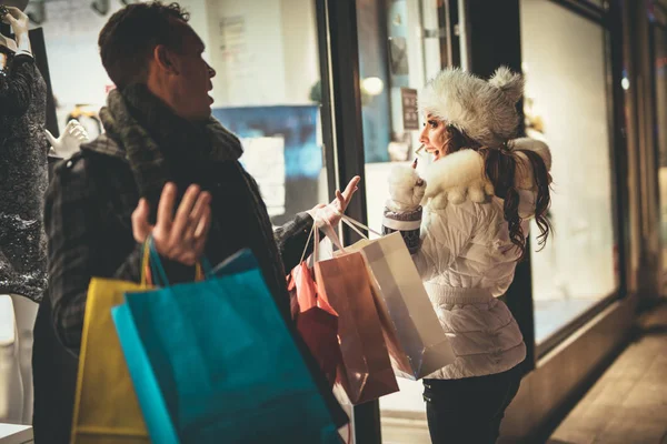 圣诞节的时候 年轻美丽的夫妇在城市街道购物 可爱的女孩祈祷她的男朋友 他们仍然在购物 而他们携带许多购物袋 — 图库照片