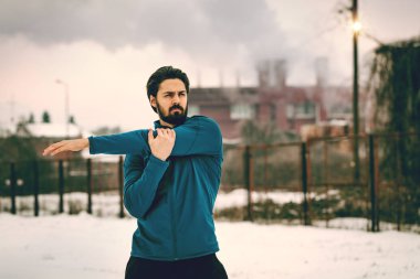 Aktif genç adam yapıyor ve germe egzersizleri eski fabrikada eski demiryolu arasında yer 