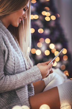Noel dekore edilmiş iç tablet bilgisayar kullanan genç gülümseyen kadın