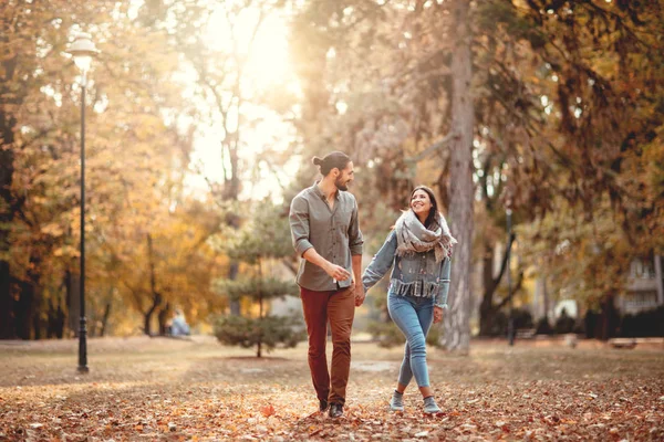年轻夫妇走在秋天阳光明媚的公园 — 图库照片