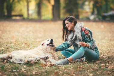 yapraklarla kaplı ve köpek ile eğleniyor zeminde oturan genç kadın