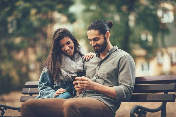 Bankta Oturan Smartphone Kullanarak Gülümseyen Çift — Stok fotoğraf