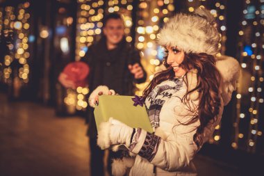 Genç kız şehirde Noel zamanda sokak veren hediye adam