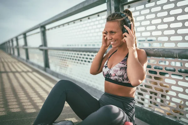 Young fitness woman resting after hard training by river bridge