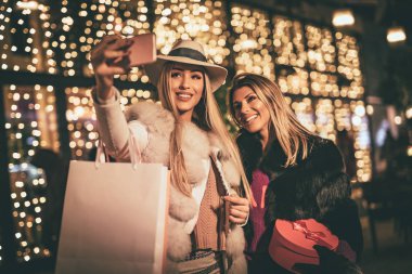 Genç kadınlarla renkli alışveriş torbaları City gece Noel zamanı, sokak yürüyüş