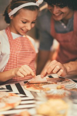 Küçük kız ve baba ketçap ve kekik pizza üzerine koyarak