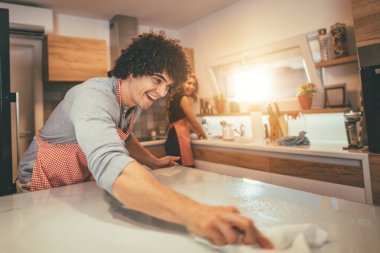 Happy young couple preparing tasty meal in kitchen.