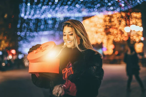 Молодая Женщина Открывает Красный Подарок Городской Улице Рождество — стоковое фото
