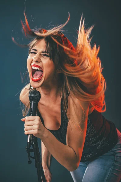 young woman singer in front of microphone singing with mouth wide open