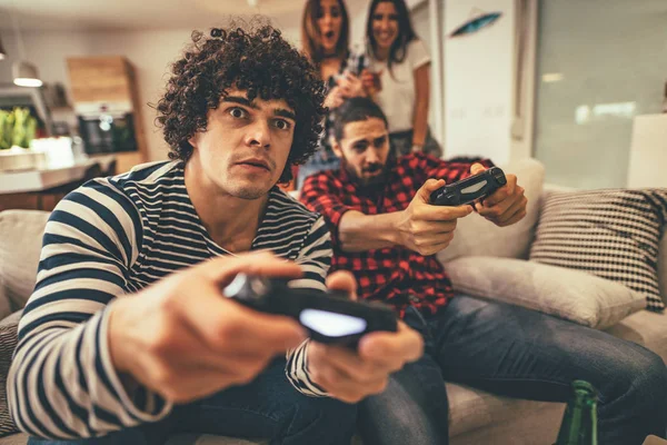Excited friends playing video games at home with beer