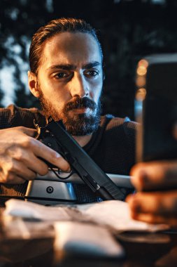Tehlikeli bir suç adam silahla smartphone cep telefonu ile mesaj alışverişi 