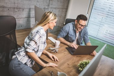 Proje hakkında konuşmak ve bir dizüstü bilgisayarda ofiste çalışan genç başarılı tasarımcılar. 
