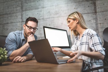 Proje hakkında konuşmak ve bir dizüstü bilgisayarda ofiste çalışan genç başarılı tasarımcılar. 