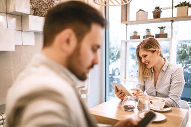 Smartphone kullanarak ve kafede kahve içme genç gülümseyen kadın