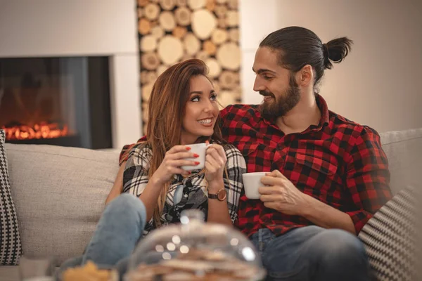 年轻夫妇坐在沙发上在家喝茶 — 图库照片
