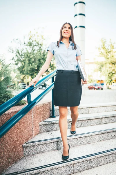 Young businesswoman walking down stairs to building