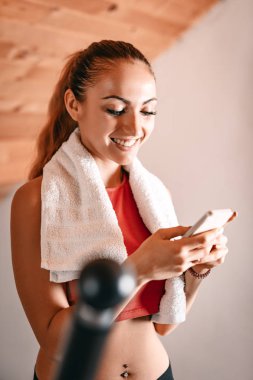 Step, evde egzersiz yaparken Smartphone kullanan genç kadın
