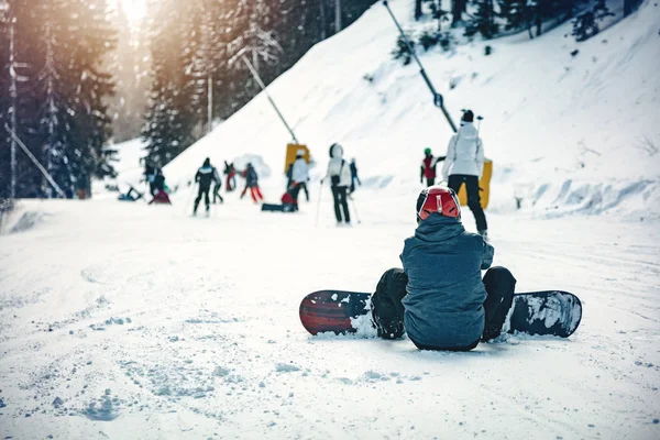 Visão Traseira Homem Com Snowboard Sentado Neve Desfrutando Dia Ensolarado — Fotografia de Stock