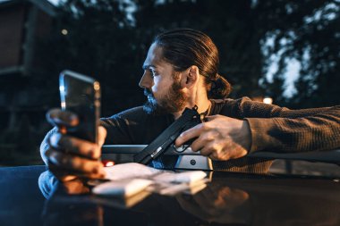 Tehlikeli bir suç adam silahla smartphone cep telefonu ile mesaj alışverişi 